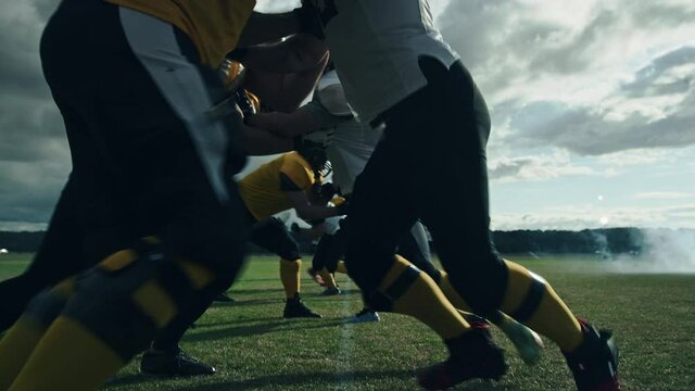 American Football Field: Two Professional Teams Clash, Attacking to Score Touchdown Points. Athletes Brutally Compete for the Ball, Tackle Each other. Dramatic Slow Motion with Immersive Cinematic