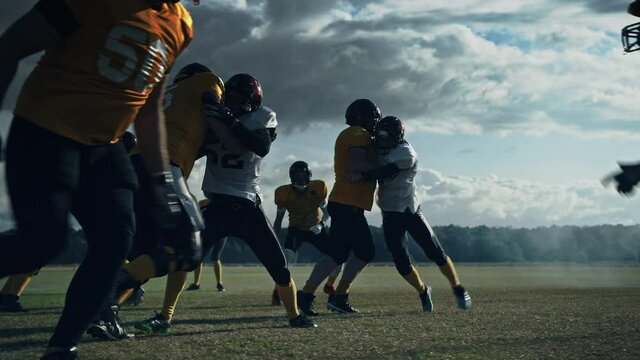 American Football Field Two Teams Compete: Players Snap Pass and Run Attacking to Score Touchdown Points. Professional Athletes Compete for the Ball, Tackle, Fight for Victory. Cinematic Slow Motion