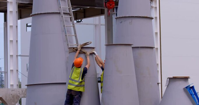 On a construction site, a workers hooks crane hook to a massive load and to move it to another location
