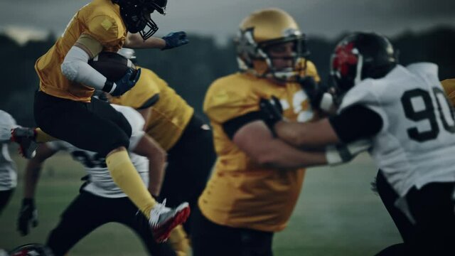 American Football Field Two Teams Compete: Successful Player Jumping Over Defense Running to Score Touchdown Points. Professional Athletes Compete for the Ball, Tackle, Fight for Championship Victory