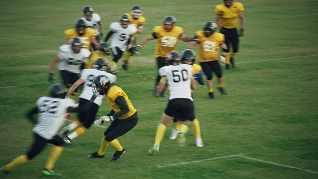 American Football Teams Start Game: Professional Players, Aggressive Face-off, Tackle, Pass, Fight for Ball and Score. Warrior Competition Full of Brutal Energy, Power, Skill. Slow Motion Wide Shot