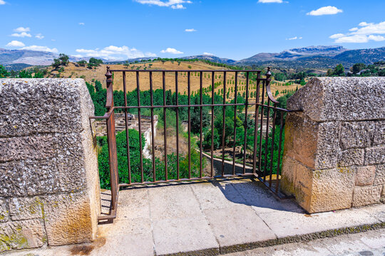 Balc&oacute;n de piedra y reja de hierro en la muralla de una ciudad medieval con unas bonitas vistas r&uacute;sticas un d&iacute;a soleado con cielo azul.