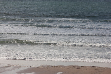 Small waves at the water's edge of a sandy beach on west coast of Ireland's Wild Atlantic Way selective focus
