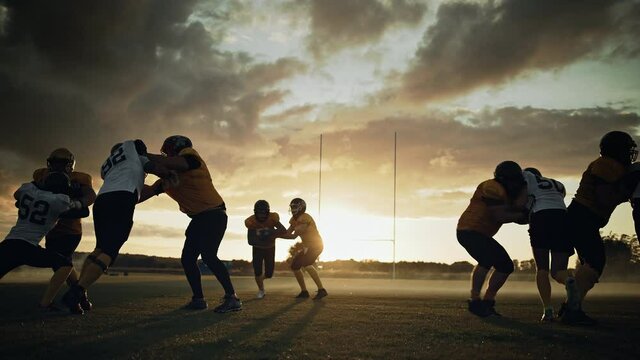 American Football Field Start of Offensive Play with a Snap Pass: Successful Player Jumping Over Defense Running to Score Touchdown Points. Professional Athletes Compete Fight for Victory