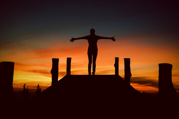 Silhouette Asian woman standing with hands up achieving looking view sky. Girl welcomes a sun. Successful woman hiker open arms on a sunrise mountain top.