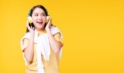 Cheerful enjoy young woman wearing headphones listening to music form smartphone and dancing relax over isolated yellow background. Lifestyle leisure with hobby concept.