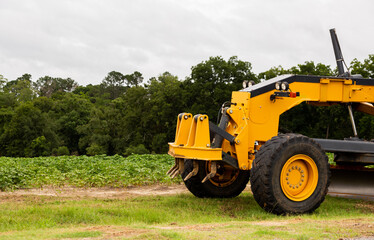 Obraz premium Farm Machine Next to a Plowed Field with Trees in the Background