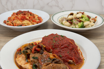 Italian cuisine feast with a full table of food with chicken pollo compagnola with mushrooms served with pasta and marinara sauce