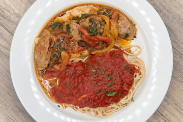Overhead view of double chicken breast served with spaghetti with marinara sauce as pollo campagnola