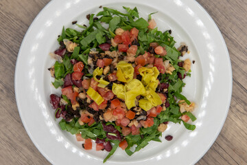 Overhead view of chopped spinach piled high on a plate with colorful mixed vegetables and peppers for a heathy appetizer to a meal