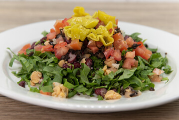 Chopped spinach piled high on a plate with colorful mixed vegetables and peppers for a heathy appetizer to a meal