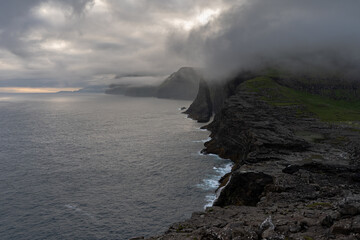 Beautiful aerial view of the Bøsdalafossur waterfall and Trælanípan magnificent landmarks in the Faroe Islands