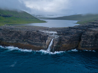 Beautiful aerial view of the Bøsdalafossur waterfall and Trælanípan magnificent landmarks in the Faroe Islands