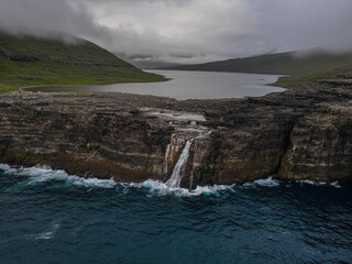 Beautiful aerial view of the Bøsdalafossur waterfall and Trælanípan magnificent landmarks in the Faroe Islands