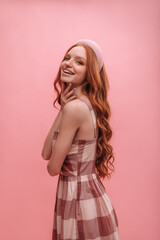 Portrait of happy smiling caucasian girl in dress with copy space. Elegant red-haired lady with wavy long hair and soft headband poses half sideways. Beauty and youth concept