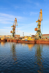 Cargo seaport. View of old harbor cranes and rusty ships near the pier. Sea port in the Arctic. Industry and infrastructure in the Far North of Russia. Beringovsky, Chukotka, Siberia, Russia.