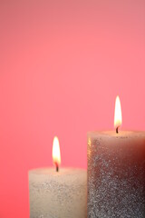 Candle flame. One shiny candle close-up on pink background.Candles