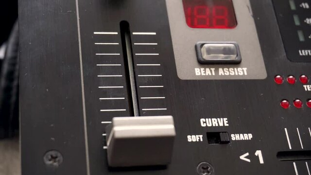 Close-up of fingers lowering a fader on the mixing console