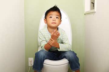 日本の水洗トイレに座っている男の子。
