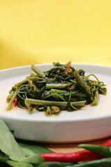 water spinach served in a bowl with yellow background