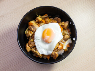 A bowl of teriyaki chicken with fried egg on top.