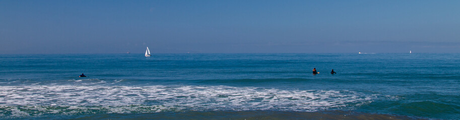 Fototapeta premium Surfers and Sailboat in the Pacific Ocean near Ventura California United States