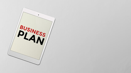 Business plan written on the screen of computer tablet. Business plan text showing up on a white computer table laying on the white background.