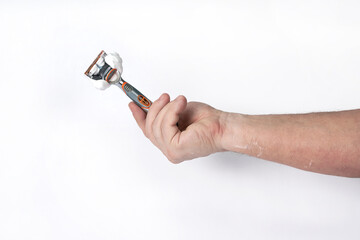 Hand holds a shaving razor with shaving foam on a white background