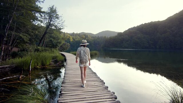 Young traveler in shorts walking on a wooden bridge near Plitvice Lake