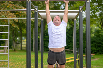 Obraz premium Senior man working out on parallel bars in a park in spring