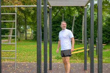 Athletic man in sportswear standing below parallel bars
