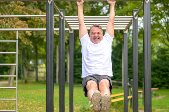 Senior man working out on parallel bars in a park in spring