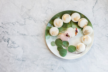 White macaroons are on a plate. Delicious light cookies on a plate on a light background. Bakery