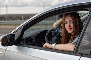 Obraz na płótnie Canvas beautiful redhead girl driving a car