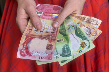 Woman holding various Iraqi dinar banknotes. - obrazy, fototapety, plakaty