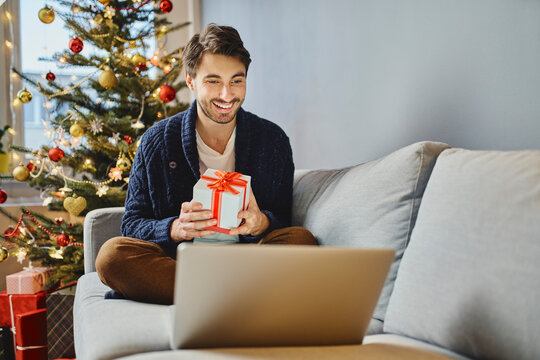 Man opening Christmas gift during video call with family