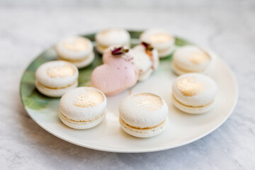 White macaroons are on a plate. Delicious light cookies on a plate on a light background. Bakery