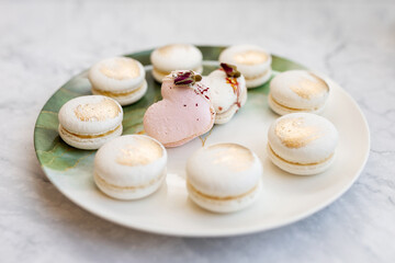 White macaroons are on a plate. Delicious light cookies on a plate on a light background. Bakery