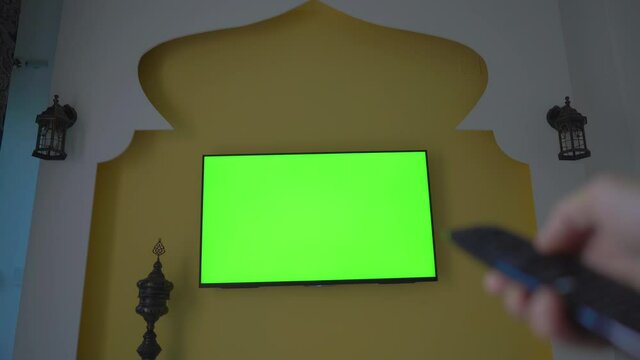 Wall with TV and green screen in the style of the Middle East and North Africa. Hand with remote control. FIFA Arab Cup in Qatar