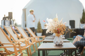 On the table is a decorative vase with dried flowers. Beautiful summer location for relaxation