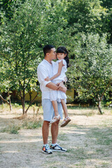 Obraz premium Longshot of asian father holding his daughter in hands, kissing her in a cheek