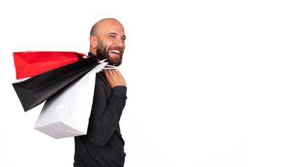 Happy young man with beard carries shopping bags over shoulder on white background. Horizontal...