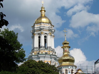 Fototapeta na wymiar The incredible beauty of the golden tops of the temples of the Kiev-Pechersk Lavra under the rays of the summer sun on a background of blue sky.