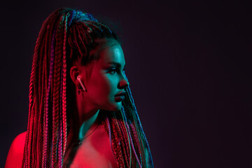 woman with dreadlocks is listening to music on earphones