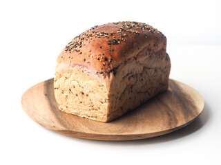 Whole cereal bread loaf on wooden round plate on white background