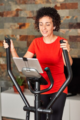 Fototapeta na wymiar Woman exercising at home with online cross training elliptical class