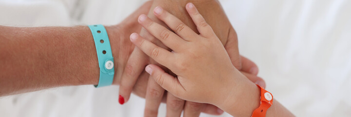 Hands of parents and child with bracelet are joined together