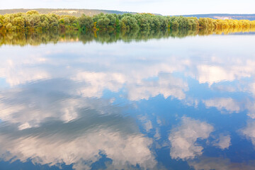 Riverside trees and clouds reflection in the water . Danube river in the autumn 