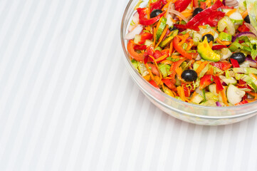 Glass salad bowl on a white stripy tablecloth