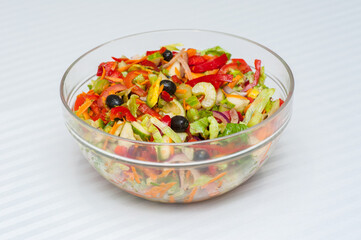 Glass salad bowl on a white stripy tablecloth